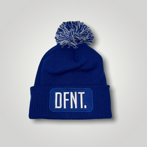 A royal blue beanie hat with a two tone blue and white bobble on top. The hat is branded with DFNT. embroidered on the centre patch in white. It is soft to the touch and has a double layer knit and ribbed cuff.