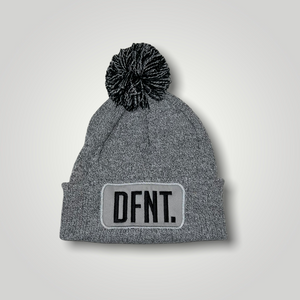 A light grey beanie hat with a two tone grey and black bobble on top. The hat is branded with DFNT. embroidered on the centre patch in black. It is soft to the touch and has a double layer knit and ribbed cuff.
