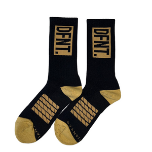 DFNT. performance socks in black. The logo is negative space in gold to match the heel and toe. The Defiant Co is woven in to the bottom of the sock in gold along with some stripes that track the slightly elasticated sole to help keep them in place during workouts.